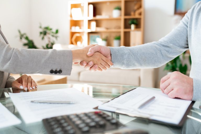 Handshake of businessman and businesswoman sitting by table